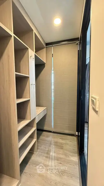 Spacious walk-in closet with modern wooden shelving and natural light.