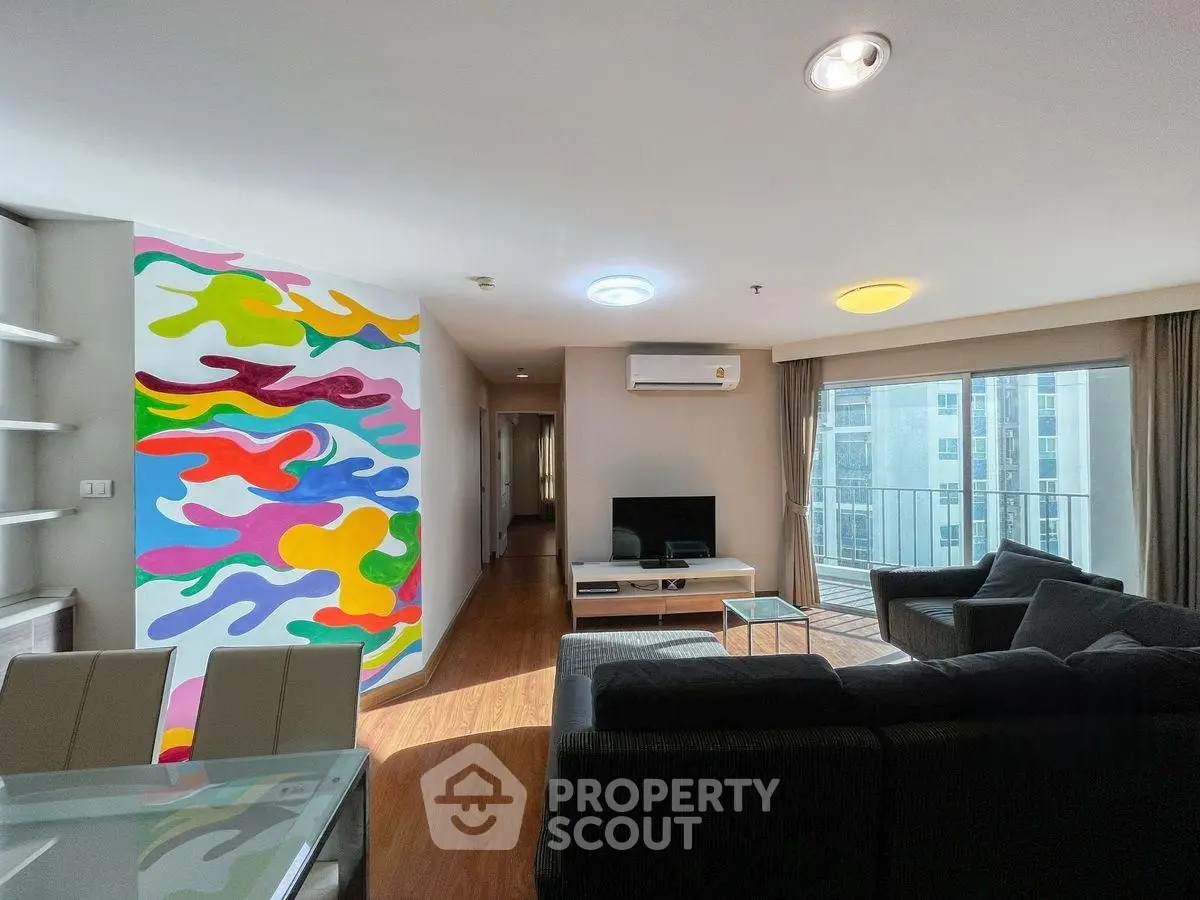 Spacious living room with vibrant mural and modern furnishings in high-rise apartment