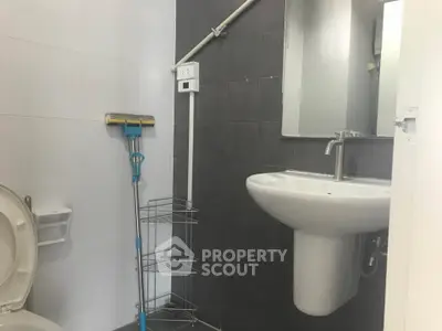 Compact bathroom with modern sink and cleaning supplies