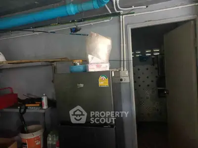 Compact kitchen storage area with refrigerator and open shelving
