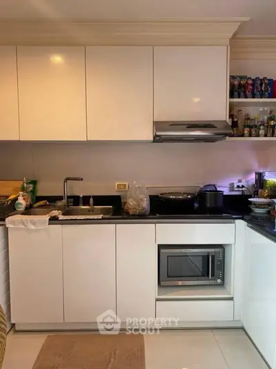Modern kitchen with sleek white cabinets and built-in microwave, perfect for culinary enthusiasts.