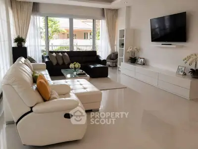 Spacious modern living room with sleek furniture and large windows offering natural light.