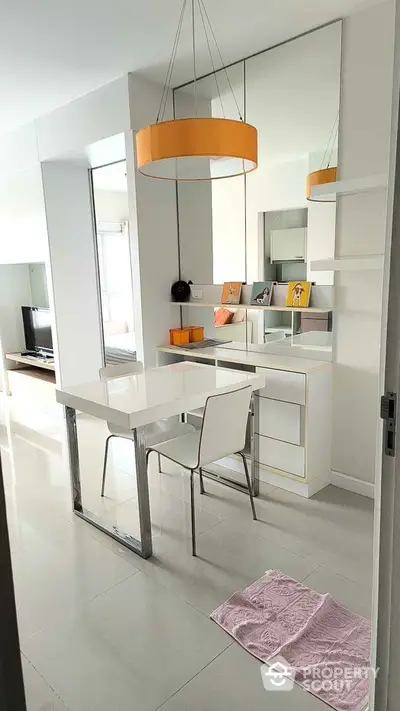 Modern dining area with sleek white furniture and stylish lighting in a contemporary apartment.