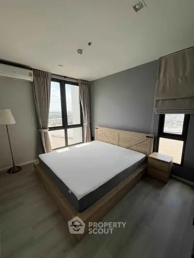 Modern bedroom with large windows and stylish decor in a high-rise apartment.