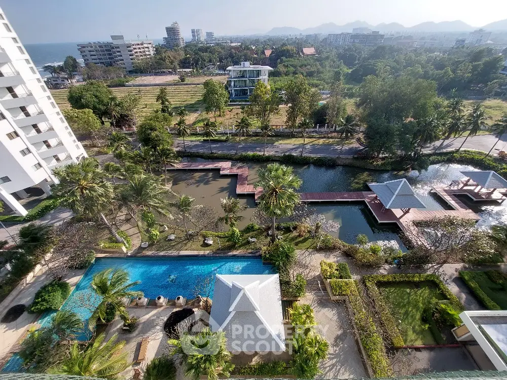 Stunning aerial view of luxury resort with pool and lush gardens near the coastline.