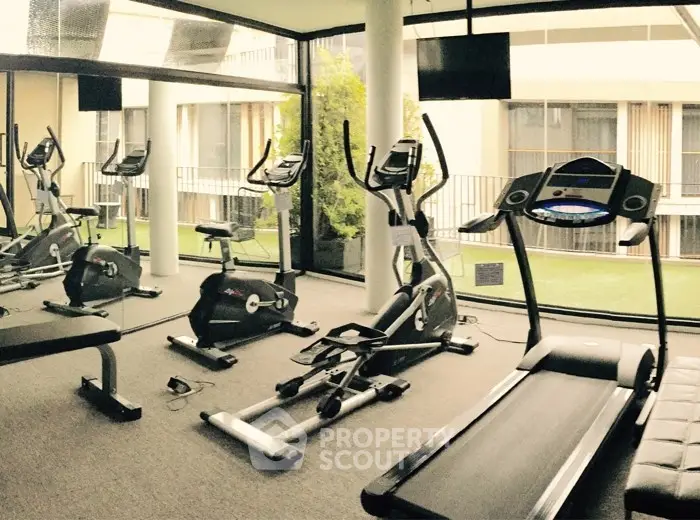 Modern gym with exercise equipment and large windows in luxury apartment building.