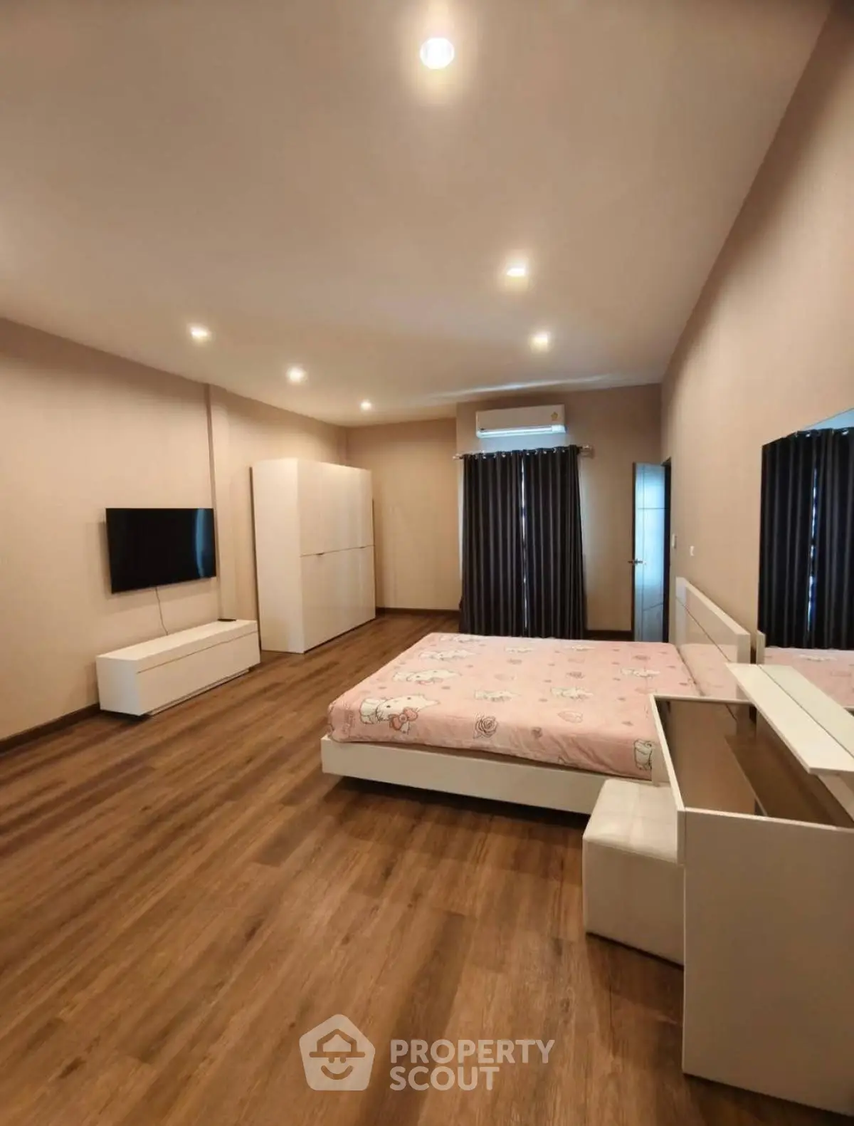 Spacious modern bedroom with wooden flooring and stylish furniture