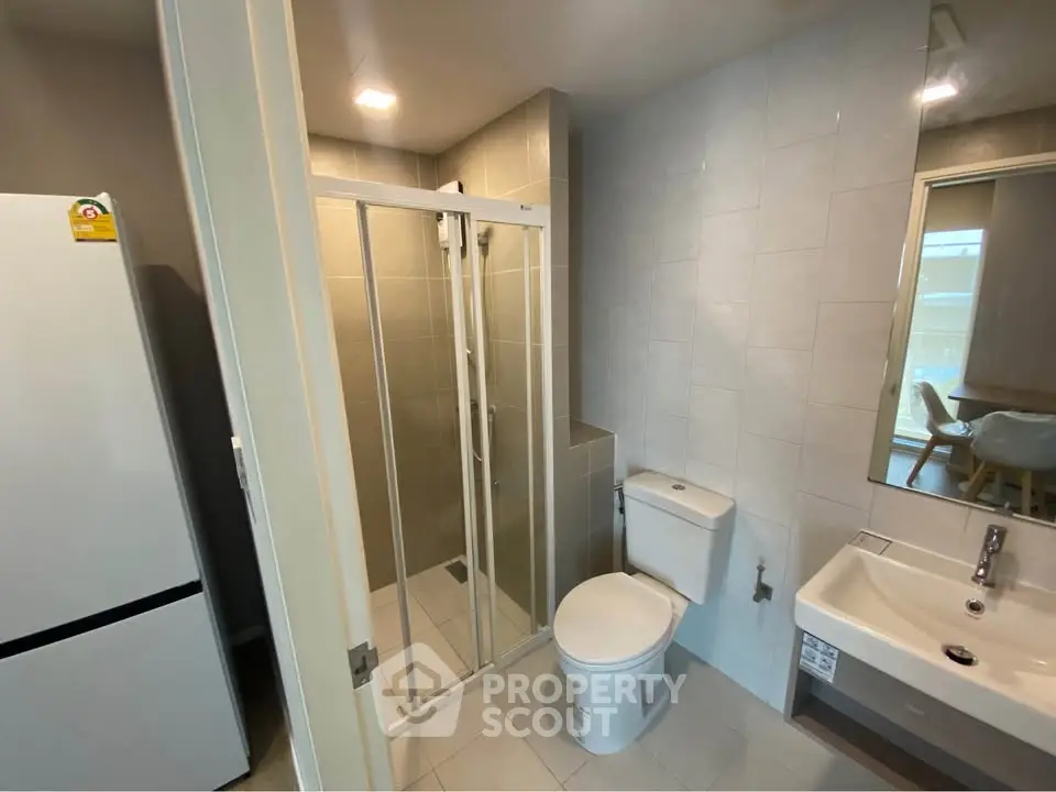 Modern bathroom with glass shower, toilet, and sink in contemporary apartment.