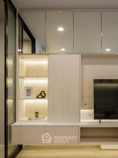 Modern living room with sleek built-in shelving and flat-screen TV, showcasing elegant interior design.