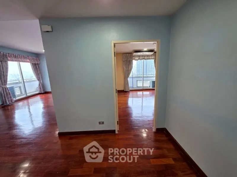 Spacious apartment with hardwood floors and large windows offering city views.