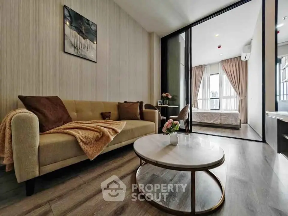 Modern living room with elegant decor and view into a cozy bedroom, featuring stylish furniture and warm ambiance.