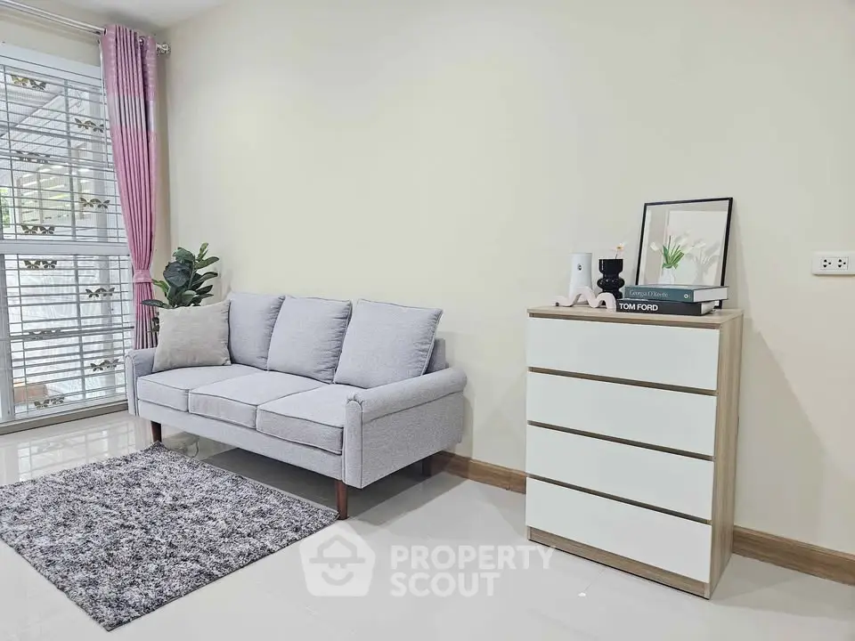 Modern living room with cozy gray sofa and stylish chest of drawers.
