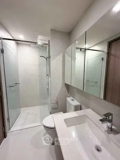 Modern bathroom with glass shower and sleek fixtures in a contemporary apartment.
