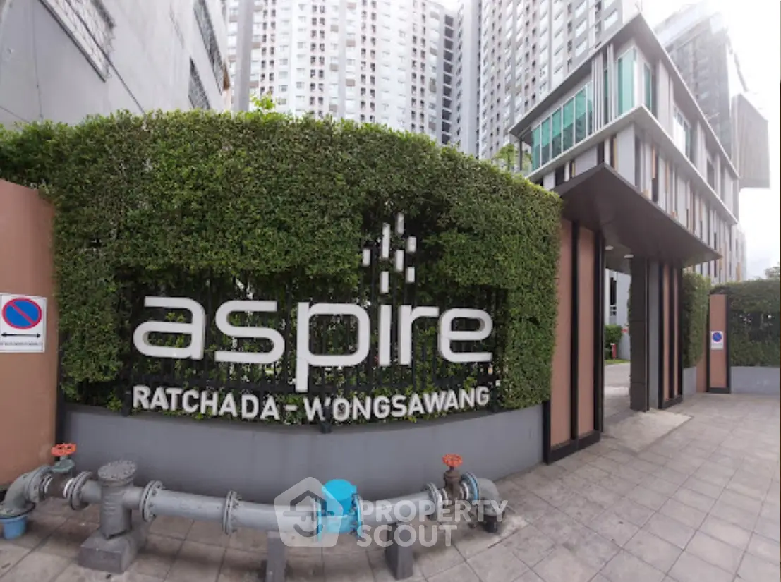 Modern condominium entrance with lush greenery and sleek design at Aspire Ratchada Wongsawang.