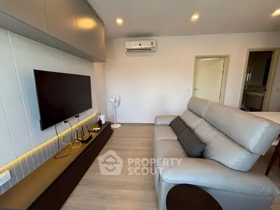 Modern living room with sleek design, featuring a comfortable sofa and wall-mounted TV, perfect for relaxation.