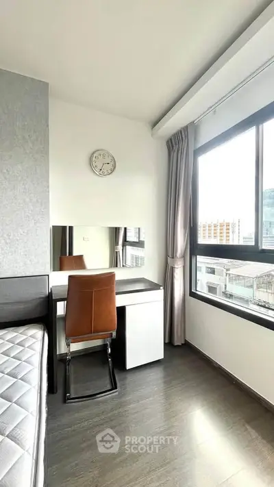 Modern bedroom with sleek desk and large window offering city views.
