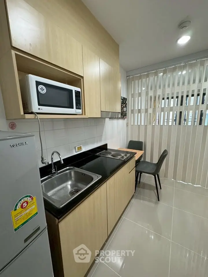 Modern kitchen with sleek cabinetry, microwave, and dining area in a stylish apartment.