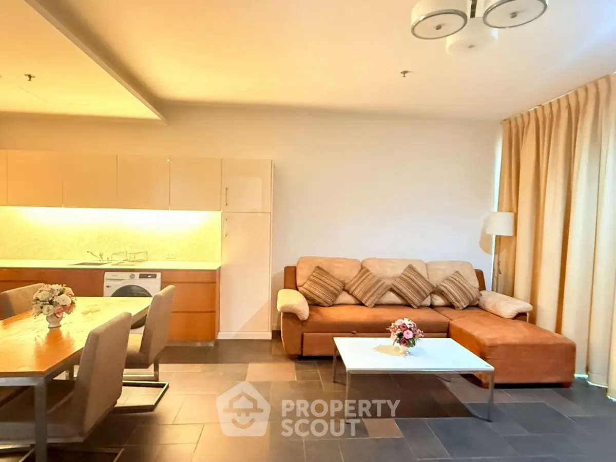 Spacious living room with modern furniture and open kitchen layout, perfect for entertaining.
