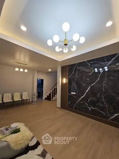 Spacious modern living room with elegant lighting and marble accent wall