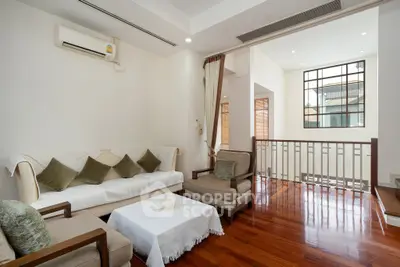 Elegant living room with wooden flooring and natural light, featuring cozy seating and modern decor.