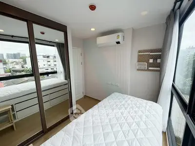 Modern bedroom with large windows and mirrored wardrobe in urban apartment