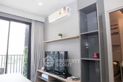 Modern living room with balcony, air conditioning, and stylish shelving unit.