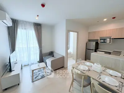 Modern open-plan living room with kitchen and dining area, featuring sleek furniture and natural light.