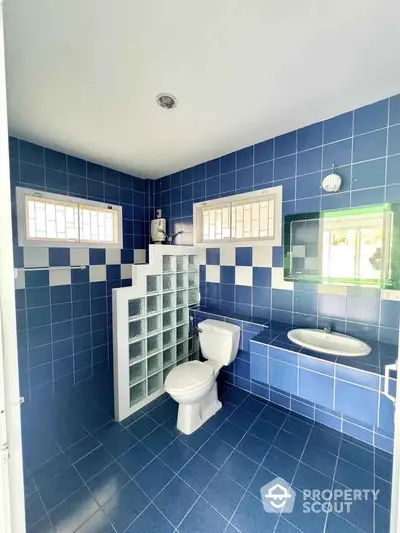 Spacious blue-tiled bathroom with bathtub and modern fixtures