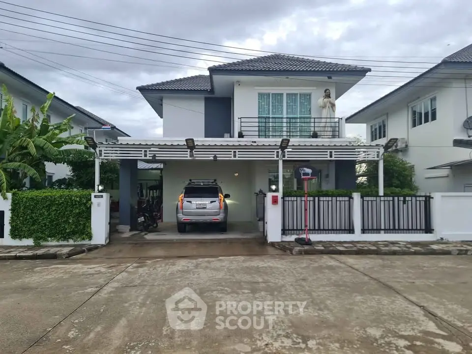 Modern two-story house with carport and gated driveway in a suburban neighborhood.