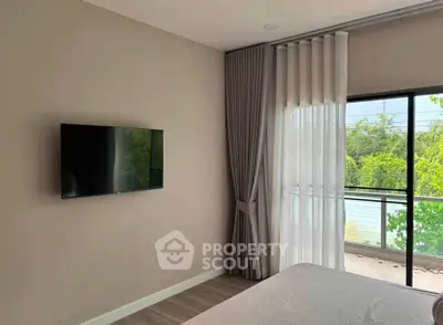 Modern bedroom with wall-mounted TV and large window with lush greenery view.