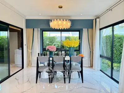 Elegant dining room with modern chandelier and large windows overlooking lush garden