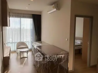 Modern apartment interior with dining area and bedroom view, featuring sleek furniture and natural light.