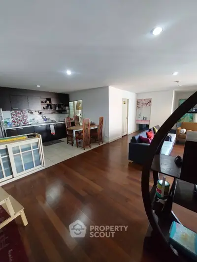 Spacious open-plan living room with modern kitchen and dining area, featuring elegant wooden flooring.