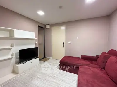 Modern living room with red sofa and wall-mounted TV in a cozy apartment.