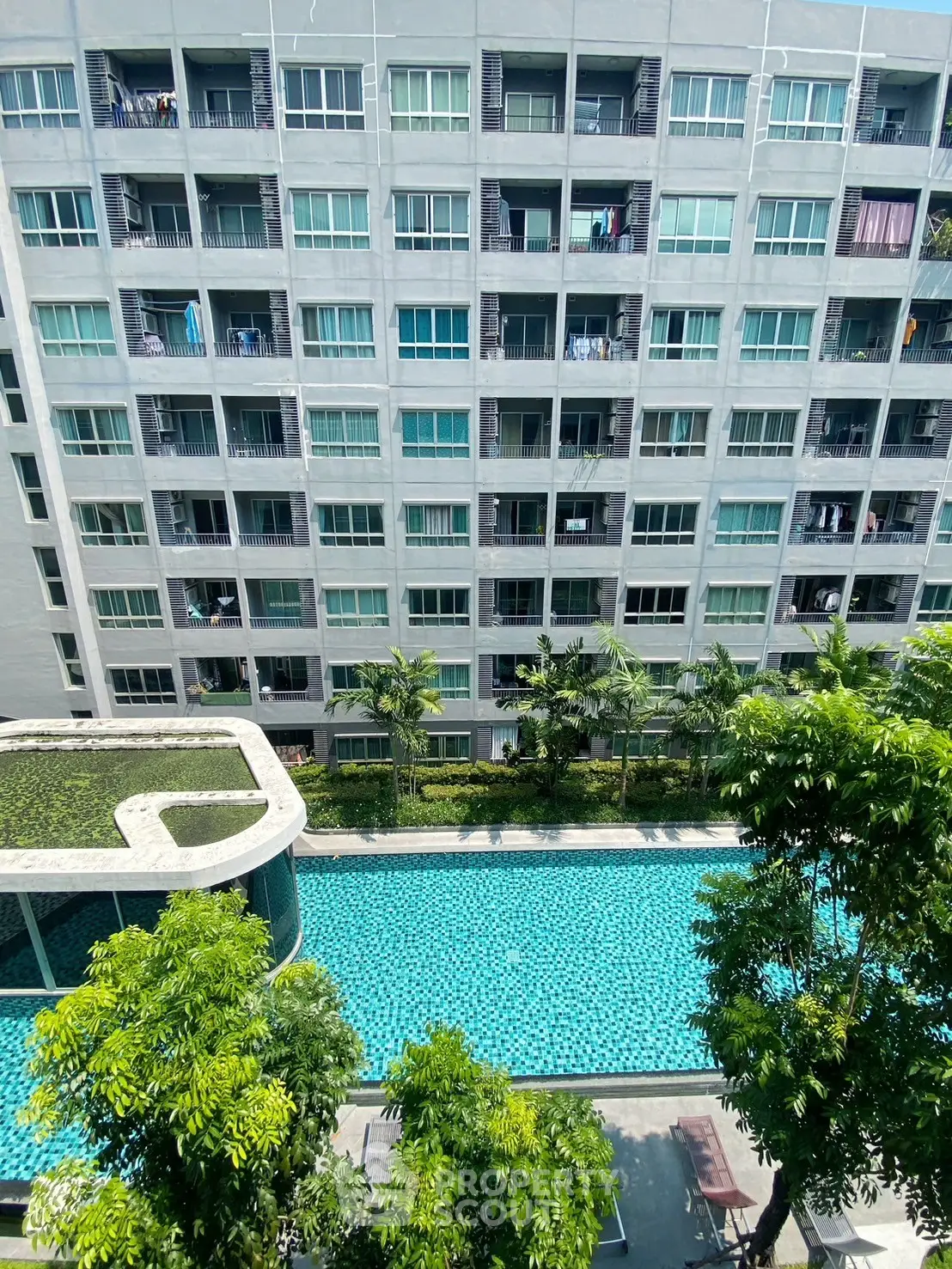 Modern apartment building with a refreshing pool view and lush greenery.