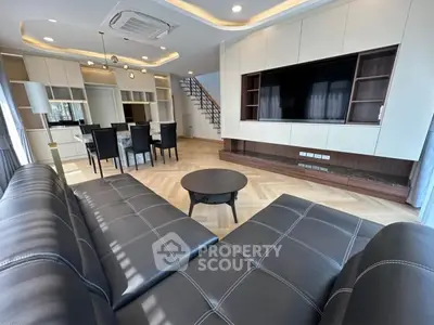 Luxurious modern living room with sleek black leather sofa, elegant dining area, and stylish open kitchen.
