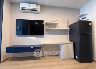 Modern living room with sleek TV setup and stylish black refrigerator