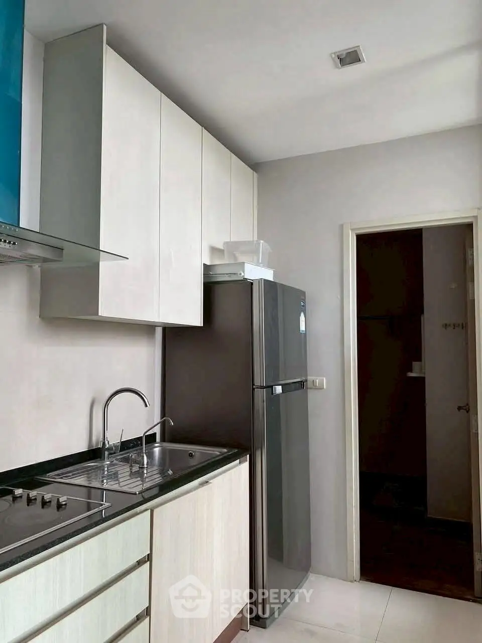Modern kitchen with sleek cabinets and stainless steel fridge in compact layout.
