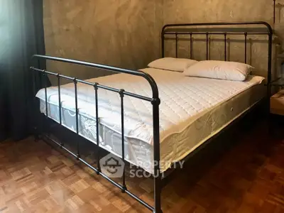 Cozy bedroom with rustic metal bed frame and parquet flooring