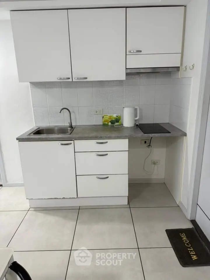 Compact kitchen with white cabinets and electric stove in modern apartment