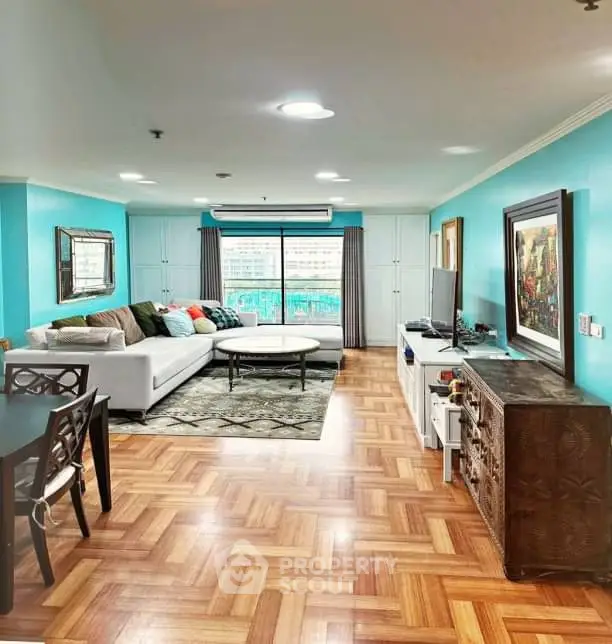 Spacious living room with vibrant decor and large windows offering city views.