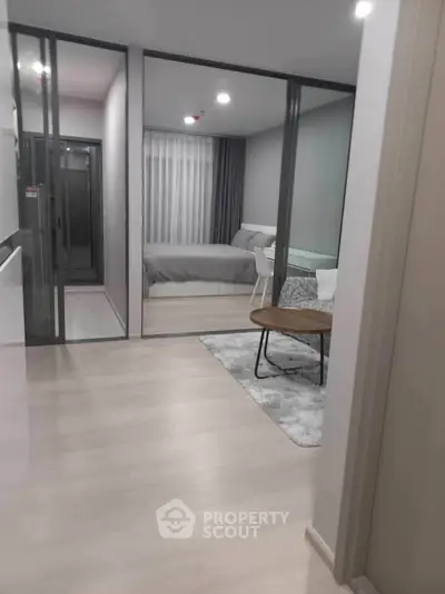 Modern apartment interior with glass partitioned bedroom and cozy living area.