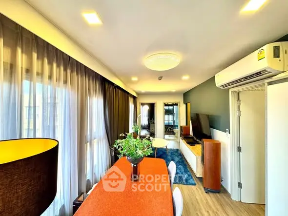 Modern living room with stylish decor and natural light, featuring a dining area and air conditioning.