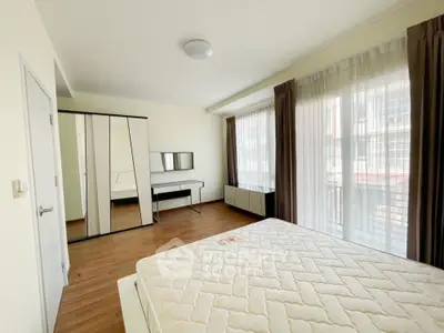 Spacious bedroom with large windows allowing ample natural light, hardwood floors, and modern furnishings, perfect for a restful retreat.