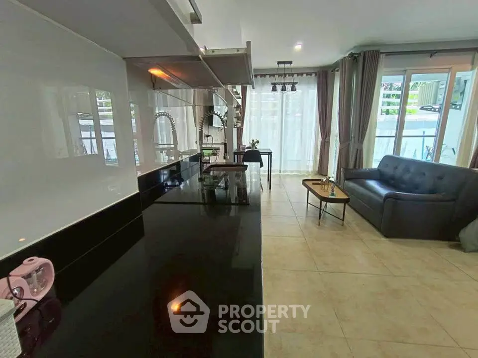 Modern open-layout living room with sleek kitchen and cozy seating area.