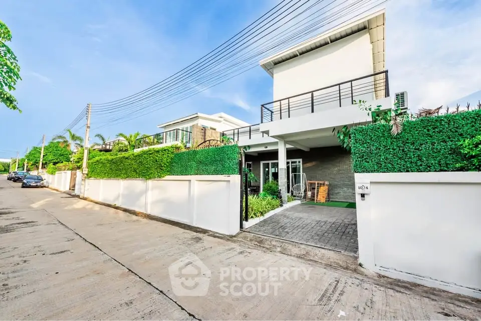 Modern two-story house with lush greenery and spacious driveway in a serene neighborhood.