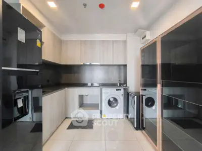Modern kitchen with sleek cabinetry and built-in appliances, including a washing machine and fridge.