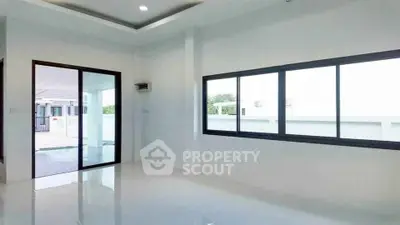 Spacious modern interior with large windows and sliding glass door, perfect for natural light.