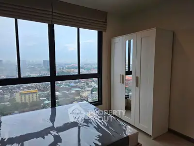 Modern bedroom with large window offering stunning city views and sleek white wardrobe.