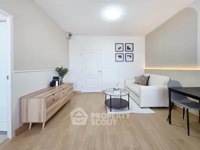 Modern living room with stylish decor and wooden flooring, featuring a cozy white sofa and elegant furniture.